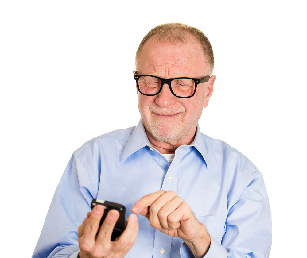 Closeup portrait, frustrated angry senior man, nerd black glasses, seeing bad news email text on cellphone, isolated white background. Negative human facial expressions, emotion feeling